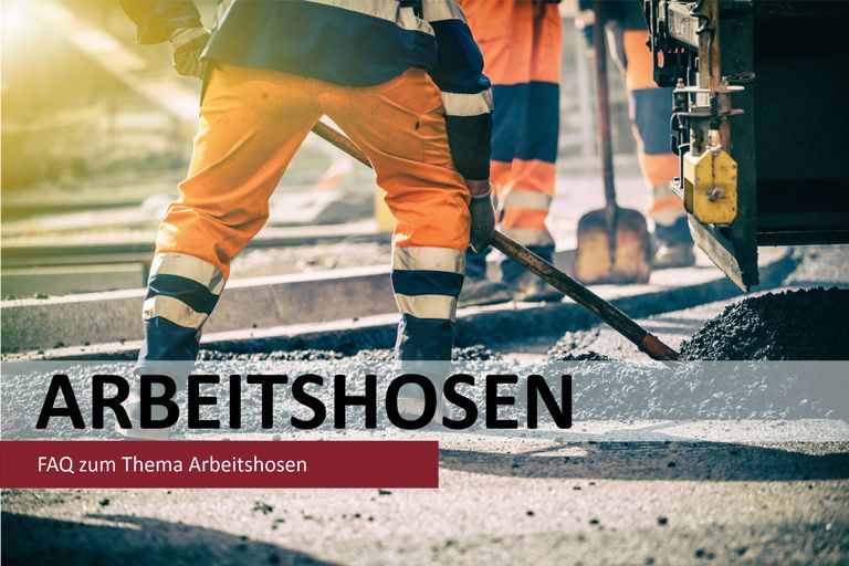 Zwei Arbeiter in orangefarbenen Arbeitshosen bei Bauarbeiten auf Schienen.
